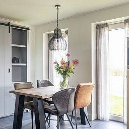 Stijlvolle eetkamer van De Deel, vakantieappartement in Hollum, Ameland, met houten tafel en designverlichting.