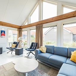 Helles Wohnzimmer in Waddenlodge 6+2, einem Ferienhaus in Hollum, Ameland mit grossen Fenstern und gemuetlicher Sitzecke auf den Watteninseln.