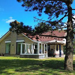 Gemuetliches Wohnzimmer des Ferienhauses "De Vrijheid" in Hollum auf Ameland, modern eingerichtet und mit Blick auf die gruene Umgebung.