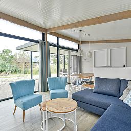 Lichte woonkamer in Vrijstaande woning in Hollum, Ameland met uitzicht op de omgeving.