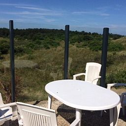 Terrasse des Parnassia-Bungalows in Nes, Ameland mit Blick auf die gruene Umgebung.