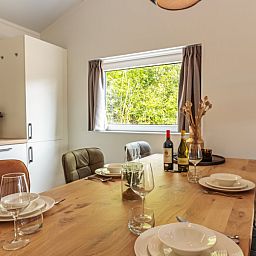 Dining table in Nesserduinen 42D, vacation home in Nes, Ameland overlooking green surroundings.