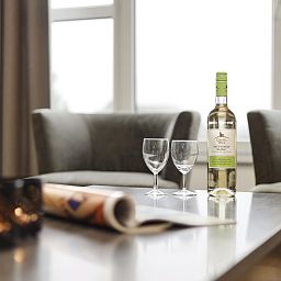 Stijlvolle zithoek in Ameland State appartement in Nes, Ameland, met wijn en glazen op de tafel.