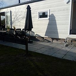 Zonnig terras van chalet Protter in Buren, Ameland, ideaal voor buiten dineren en ontspanning.