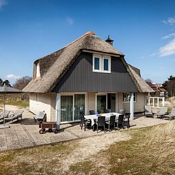 Zonnig terras van Villa Rietberg op Schiermonnikoog, vakantiehuis met buitenzitje en natuur.