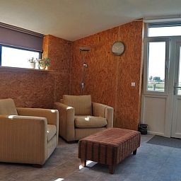 Gezellige eetruimte in Vakantiehuisje in It Heidenskip, gelegen aan de Friese meren, met houten tafel en comfortabele stoelen.