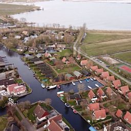 Aerial view of Bungalow Sneekermeer with sailboat in Goingarijp, located on the waters of the Frisian lakes for a relaxing vacation.