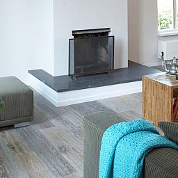 Cozy living room in Holiday Home in Kollumerpomp, Lauwersmeer, with fireplace and comfortable seating area for relaxation.