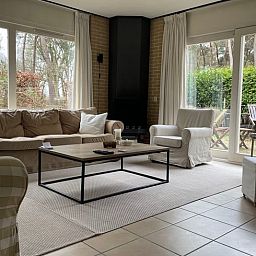 Lichte woonkamer van Vakantiehuis in Spier met uitzicht op de groene omgeving van Drenthe.