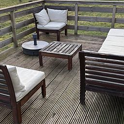 Houten veranda van Vakantiehuisje in Wezuperbrug met uitzicht op groene velden in Midden Drenthe, Drenthe.