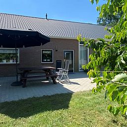 Terrasse mit Sonnenschirm im Ferienhaus in Beilen, Zentral-Drenthe, ideal fuer Mahlzeiten im Freien.