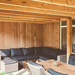 Gezellige veranda van Huisje in Gasselte, vakantiehuis in Midden Drenthe, met comfortabele zithoek en houten afwerking voor ontspanning.