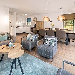Gemuetliches Wohnzimmer im Stuifzand Wellness Bungalow 8, Ferienhaus in Hooghalen, Zentral-Drenthe, mit moderner Einrichtung und Blick auf die Natur.