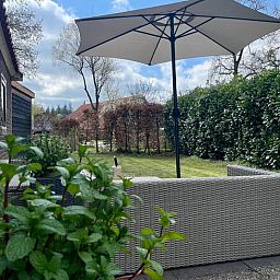 Terras met parasol bij Vakantiehuisje in Hooghalen, geniet van de buitenlucht in Midden Drenthe, Drenthe.