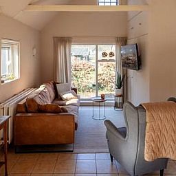 Lichte woonkamer in Vakantiehuisje in Hooghalen met comfortabele zitbank, ideaal voor ontspanning in Midden Drenthe, Drenthe.