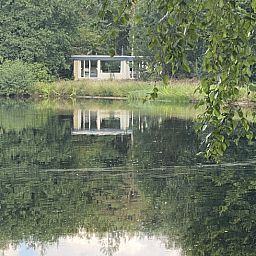 Vakantiehuis Huisje in Een, Drenthe weerspiegeld in een rustige vijver.