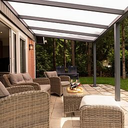 Entspannen Sie sich auf der grossen Terrasse des Huisje in Norg, einem Ferienhaus in Norg, Nord-Drenthe, umgeben von gruener Natur und Ruhe.