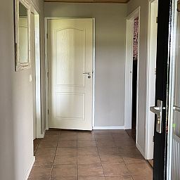 Lichte entree van vakantiehuis DG1879 in Borger, Noord Drenthe met tegelvloer en spiegel.