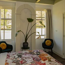 Cozy bedroom in a cottage in Veenhuizen, North Drenthe, with colorful bedding and a view of the green surroundings.
