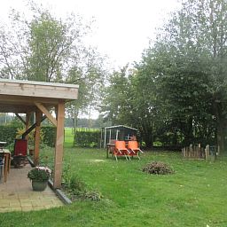 Geniet van de groene tuin en het overdekte terras bij Vakantiehuis in Drouwen, gelegen in het serene Noord Drenthe, Drenthe.
