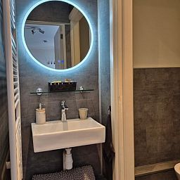 Modernes Badezimmer in Cottage in Dalerveen, Ferienhaus in Sued-Ost-Drenthe mit stilvollem Waschbecken und beleuchtetem Spiegel.