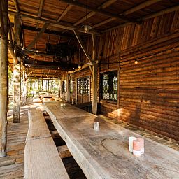 Cozy porch of Huisje in Erm, a vacation home in Southeast Drenthe, with wooden tables and views of the surrounding nature.