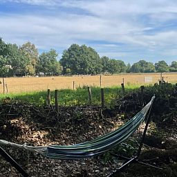 Ontspan in de hangmat bij Vakantiehuisje in Doldersum, Zuidwest Drenthe, met uitzicht op weidse velden en natuur.