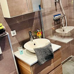 Essecke im Ferienhaus DG1706, Havelte, Drenthe mit bunten Stuehlen und Blumen.