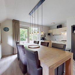 Gezellige eetruimte in vakantiehuis Borre Bos, Diever, met moderne keuken en uitzicht op de groene omgeving van Zuidwest Drenthe.