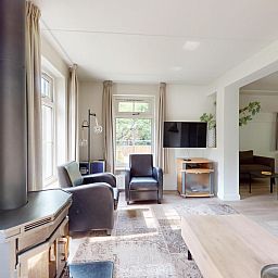 Gezellige woonkamer in vakantiehuis Borre Bos, Diever, met houtkachel en moderne inrichting, ideaal voor ontspanning in Zuidwest Drenthe.