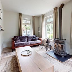 Gezellige woonkamer van vakantiehuis Borre Bos in Diever, Drenthe, met houtkachel en comfortabele bank.