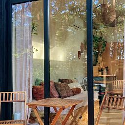 Gemuetliche Sitzecke mit Glasfassade in Cottage in Zuidwolde, Ferienhaus in Suedwest-Drenthe, umgeben von ruhiger Natur.