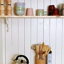 Gemuetliche Kuechenecke in Cottage in Zuidwolde, Ferienhaus in Zuidwolde, Drenthe mit Wandregalen aus Holz und bunten Tassen.