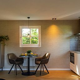 Gemuetlicher Innenbereich des Ferienhauses in Ruinen, Suedwest-Drenthe, mit einer modernen Kueche und einem Essbereich fuer einen entspannten Aufenthalt.