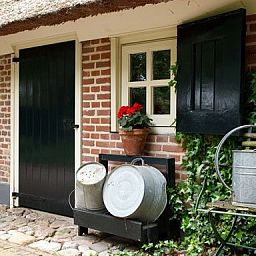 Rustikale Terrasse in Hoeve den Anholt in Ruinen, Drenthe, mit bunten Blumen und authentischen Details.