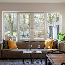 Gezellige woonkamer in Vakantiehuisje in Dwingeloo, Drenthe, met uitzicht op de natuurrijke omgeving.