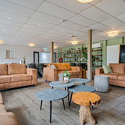 Stijlvolle woonkamer in Groepsaccommodatie de Komeet, een vakantiehuis in Dwingeloo, Zuidwest Drenthe, met comfortabele banken en moderne inrichting.