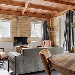 Cozy living room of Hooiberglodge in Dwingeloo, Southwest Drenthe. Enjoy a cozy vacation home with wooden interior and comfortable seating area.