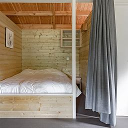 Attractive bedroom in the Hooiberglodge, a vacation home in Dwingeloo, Southwest Drenthe, with wooden interior and cozy feel.
