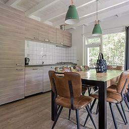 Gezellige eetkamer in Bungalow Maan, een vakantiehuis in Dwingeloo, Zuidwest Drenthe. Moderne keuken en ruime tafel voor familiediners.