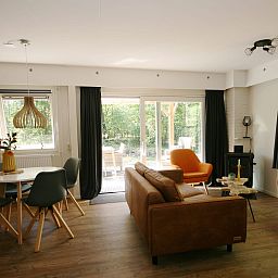 Gezellige woonkamer van Bungalow Mars in Dwingeloo, Zuidwest Drenthe, met uitzicht op terras en groene omgeving.