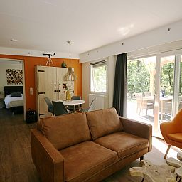 Gezellige woonkamer van Bungalow Mars in Dwingeloo, Zuidwest Drenthe. Licht interieur met terrasuitzicht in een bosrijke omgeving.