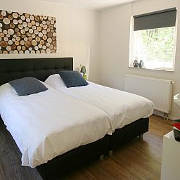 Sfeervolle slaapkamer in Bungalow Mars, vakantiehuis in Dwingeloo, Drenthe, met comfortabel tweepersoonsbed en natuurlijke lichtinval.