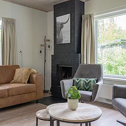 Gezellige woonkamer van Bungalow Saturnus in Dwingeloo, Drenthe, met comfortabele zitruimte en uitzicht op de groene natuur.