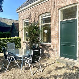 Geniet van de charmante buitenruimte van vakantiehuis DG2051 in Ruinerwold, Zuidwest Drenthe, met een gezellig terras en groene omgeving.