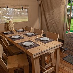 Gemuetlicher Essbereich im Ferienhaus in Ruinerwold, Ferienhaus im Suedwesten von Drenthe, mit Blick auf die gruene Umgebung und Terrasse.