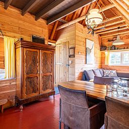 Gemuetliches Wohnzimmer im Ferienhaus in Ruinerwold, Drenthe mit Holzinterieur und bequemer Sitzecke.