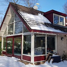 Winterse sfeer bij Vakantiehuis in Zorgvlied, Zuidwest Drenthe, met besneeuwd dak en grote ramen.