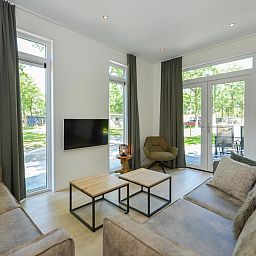 Gezellige woonkamer van chalet Onderduikershol in Zorgvlied, Zuidwest Drenthe met uitzicht op groene natuur en comfortabele zithoek.