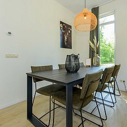 Stijlvolle eetkamer in chalet Onderduikershol, Zorgvlied, Drenthe, met moderne inrichting en uitzicht op de groene omgeving.